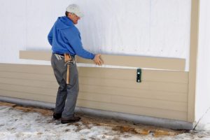 New Siding Install by worker with hammer and toolbelt
