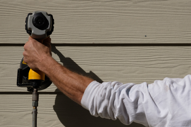 Siding Installation by worker with power tool